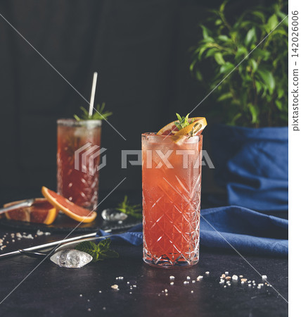 Pink Grapefruit Mezcal Paloma Cocktail in highball glass with water drops on table in real home. New life concept of quarantine, shallow depth of the field, dark background. 142026006