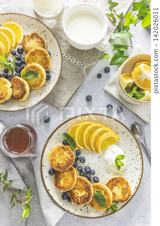 Delicious breakfast with curd fritter, ricotta fritter or cottage cheese pancakes on ceramic plate. Gourmet healthy delicious morning breakfast Delicious breakfast with curd fritter, ricotta fritter or cottage cheese pancakes on ceramic plate. Gourmet healthy delicious morning breakfast 142026011