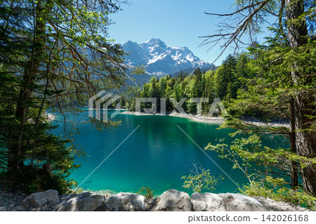 Travel landscape of Zugspitze Alps in Bavaria, Germany, scenic summer nature panorama with forest, Eibsee lake, snow mountains peak. Alpine landscape Travel landscape of Zugspitze Alps in Bavaria, Germany, scenic summer nature panorama with forest, Eibsee lake, snow mountains peak. Alpine landscape 142026168