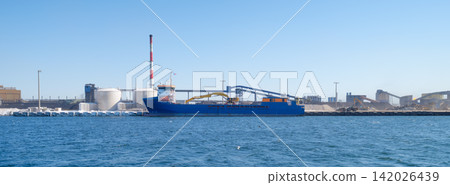 Cargo ship loading steel products at a port near a heavy industrial metallurgical plant. Cargo ship loading steel products at a port near a heavy industrial metallurgical plant. 142026439