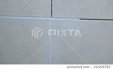 Worker using a rubber grout float to smooth grout between tiles. Carefully applying sealant to tiles joints. Workman hands smoothing caulk, using small tool to remove excess and create clean seam. Worker using a rubber grout float to smooth grout between tiles. Carefully applying sealant to tiles joints. Workman hands smoothing caulk, using small tool to remove excess and create clean seam. 142026763
