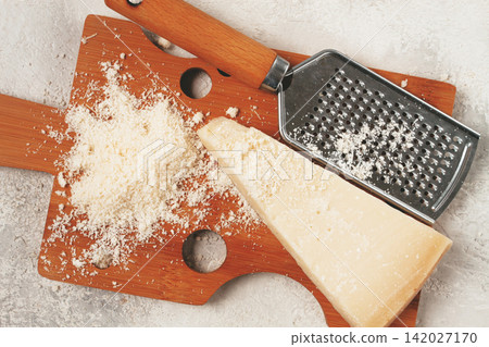 Freshly sliced and grated cheese, parmesan cheese, on a wooden chopping board, rustic style, no people 142027170