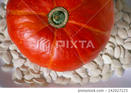 Top view of whole orange pumpkin placed on dried pumpkin seeds Top view of whole orange pumpkin placed on dried pumpkin seeds 142027225