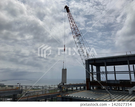 A crane lifting materials with the sea as a backdrop. 142027354