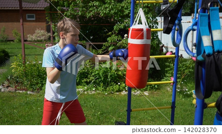 Side view of an active little student exercising with kids sports equipment in a green backyard garden zone to enhance physical fitness and precision development Side view of an active little student exercising with kids sports equipment in a green backyard garden zone to enhance physical fitness and precision development 142028370