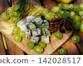 Cheese platter with grapes and rosemary on wooden board 142028517