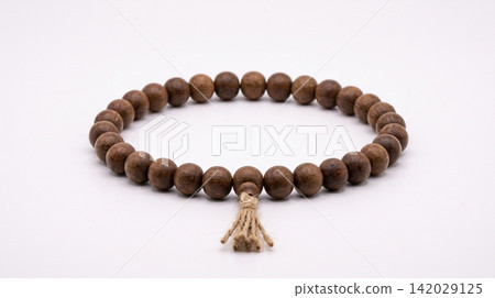 Wooden prayer beads or mala bracelet with tassel the natural wood beads are arranged in a continuous loop on a white background bracelet spiritual meditation religious accessory craftsmanship Wooden prayer beads or mala bracelet with tassel the natural wood beads are arranged in a continuous loop on a white background bracelet spiritual meditation religious accessory craftsmanship 142029125