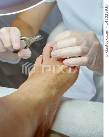 A pedicurist trims the nails with nippers. A pedicurist trims the nails with nippers. 142029930
