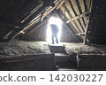 A figure standing at the entrance of a pit dwelling and the wooden framework inside the ancient building. 142030227