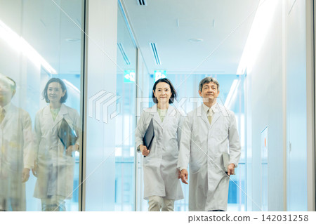 兩名五十多歲的研究人員身穿白色實驗服，走過一座研究設施。 142031258