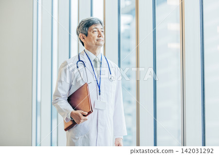 A portrait of a male doctor in his 60s wearing a white coat. A portrait of a male doctor in his 60s wearing a white coat. 142031292