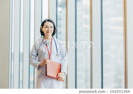 一位五十多歲的女醫生身穿白大褂的肖像。 142031304