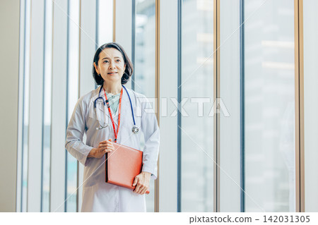 一位五十多歲的女醫生身穿白大褂的肖像。 一位五十多歲的女醫生身穿白大褂的肖像。 142031305