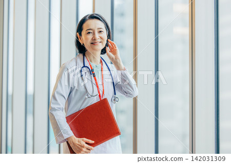 一位五十多歲的女醫生身穿白大褂的肖像。 一位五十多歲的女醫生身穿白大褂的肖像。 142031309