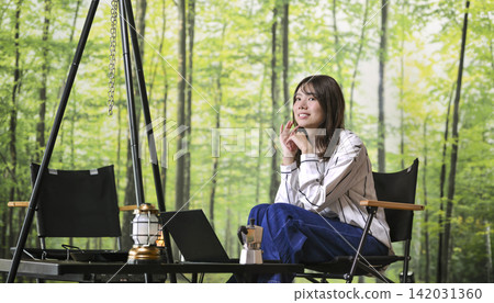 A young woman enjoying coffee and relaxing at a glamping site. A young woman enjoying coffee and relaxing at a glamping site. 142031360