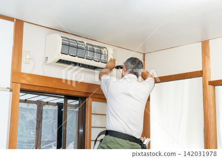 Air conditioner cleaning; a man from the air conditioner maintenance company. Air conditioner cleaning; a man from the air conditioner maintenance company. 142031978