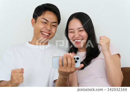 Young men and women excitedly looking at their smartphones. Young men and women excitedly looking at their smartphones. 142032169