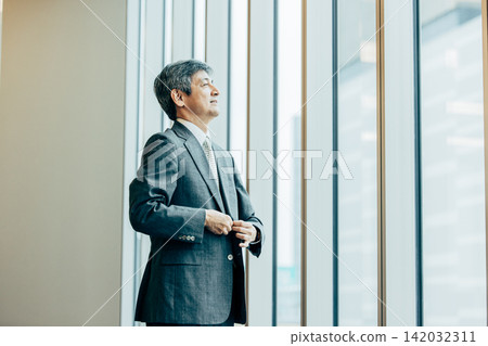 Senior businessmen wearing suit jackets in the office Senior businessmen wearing suit jackets in the office 142032311