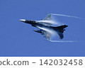 A Japan Air Self-Defense Force F-2 fighter jet turns while emitting vapor trails. 142032458