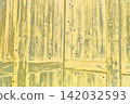 Yellowish old wooden door with wood grain texture and nail holes. 142032593
