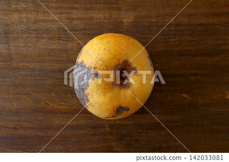 A pear with blackened skin, viewed from directly above as a table background. A pear with blackened skin, viewed from directly above as a table background. 142033081