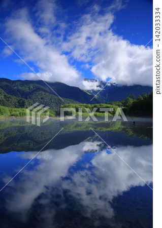 Summer clouds and clouds reflected on the lake surface Summer clouds and clouds reflected on the lake surface 142033334