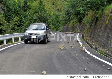 一輛SUV行駛在山路上,躲避落石。 一輛SUV行駛在山路上,躲避落石。 142034346