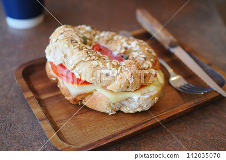 Fresh bagel with cheese and tomato on wooden tray Fresh bagel with cheese and tomato on wooden tray 142035070