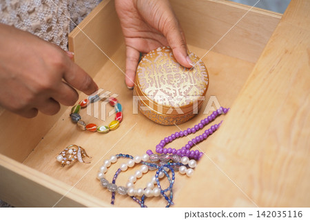 Jewelry is being organized in a wooden drawer Jewelry is being organized in a wooden drawer 142035116