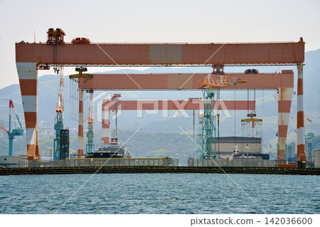 The gigantic Goliath crane of Mitsubishi Heavy Industries shipyard stands tall in Nagasaki Port, Nagasaki City, Nagasaki Prefecture. The gigantic Goliath crane of Mitsubishi Heavy Industries shipyard stands tall in Nagasaki Port, Nagasaki City, Nagasaki Prefecture. 142036600