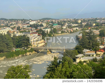 Georgian landscape. Roofs Rioni River White bridge and blue sky with white clouds. Georgia country Georgian landscape. Roofs Rioni River White bridge and blue sky with white clouds. Georgia country 142036896