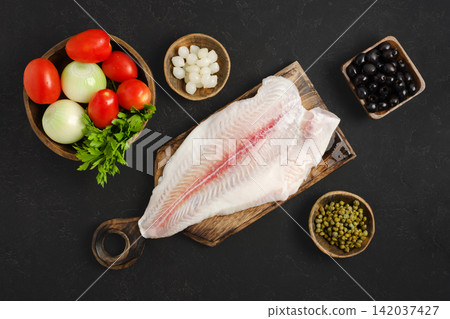 Fresh pangasius fish fillet and vegetables on wooden cutting board in kitchen Fresh pangasius fish fillet and vegetables on wooden cutting board in kitchen 142037427