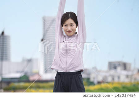 中年婦女身穿運動服伸展身體 中年婦女身穿運動服伸展身體 142037484