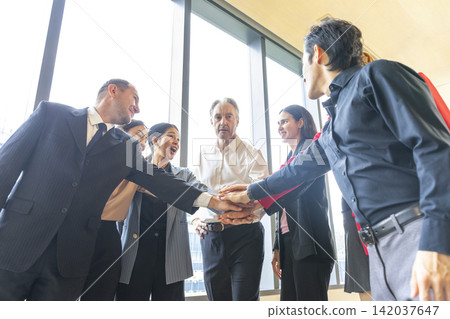 Group of multi-ethnic business colleagues standing in circle and brainstorming about new campaign, celebrating work success. Group of multi-ethnic business colleagues standing in circle and brainstorming about new campaign, celebrating work success. 142037647