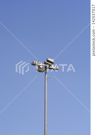 Stadium floodlight tower with security camera against blue sky Stadium floodlight tower with security camera against blue sky 142037817