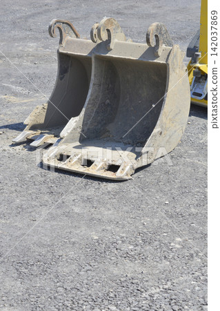 Heavy duty metal excavator bucket attachments on asphalt ground Heavy duty metal excavator bucket attachments on asphalt ground 142037869