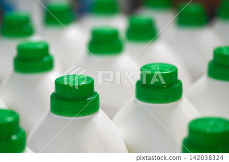 A close-up view of numerous white plastic bottles with vibrant green caps, creating a repetitive pattern A close-up view of numerous white plastic bottles with vibrant green caps, creating a repetitive pattern 142038324