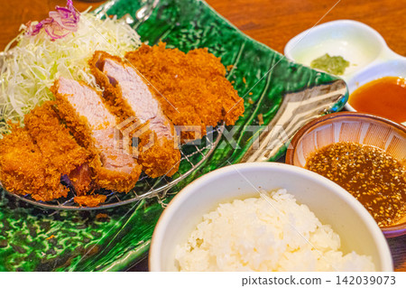 A Japanese tonkatsu set meal consisting of rice, shredded cabbage, and sauce. A Japanese tonkatsu set meal consisting of rice, shredded cabbage, and sauce. 142039073