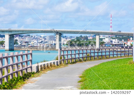A coastal park and promenade overlooking Okinawa's blue sea and a large bridge. A coastal park and promenade overlooking Okinawa's blue sea and a large bridge. 142039297