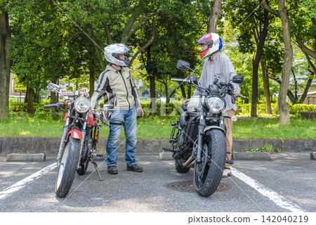 Two male motorcyclists chatting before setting off on their ride. Two male motorcyclists chatting before setting off on their ride. 142040219
