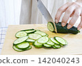 A woman's hands cutting a cucumber 142040243