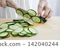 A woman's hands cutting a cucumber 142040244
