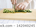 A woman's hands cutting a cucumber 142040245