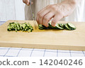 A woman's hands cutting a cucumber 142040246