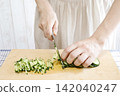 A woman's hands cutting a cucumber 142040247