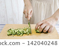 A woman's hands cutting a cucumber 142040248