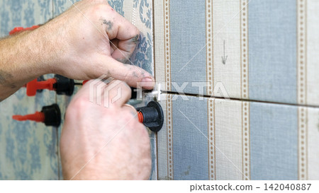 Worker Laying Ceramic Tiles on the Wall. Repairman Placing White Gray Square Tiles, Applying Adhesive. Builder Installing Tile Using Leveler, Tile Leveling Clips. Tiling. Finishing Repair Work. 4K Worker Laying Ceramic Tiles on the Wall. Repairman Placing White Gray Square Tiles, Applying Adhesive. Builder Installing Tile Using Leveler, Tile Leveling Clips. Tiling. Finishing Repair Work. 4K 142040887