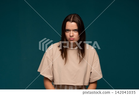 Young woman featuring angry, frustrated, and displeased expression with furrowed brow and pouting lips Young woman featuring angry, frustrated, and displeased expression with furrowed brow and pouting lips 142041035