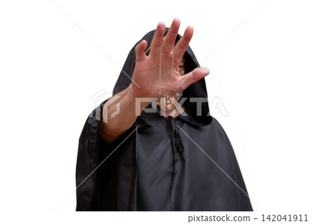 Isolated hooded monk raising hand while showing pendant toward camera 142041911