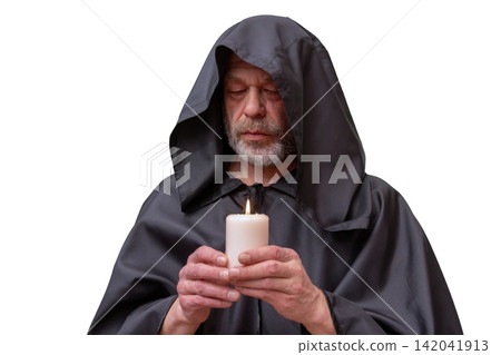 Hooded monk holding burning candle with closed eyes in quiet contemplation Hooded monk holding burning candle with closed eyes in quiet contemplation 142041913